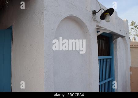 Minimalist charm of traditional Qatari architecture with rustic white walls and a sky-blue wooden door Stock Photo