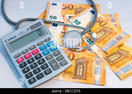Stethoscope and Calculator on €50 Bank Notes on a White Background. Stock Photo