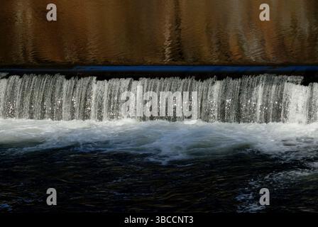 Small waterfall over a weir with light reflections, Germany Stock Photo