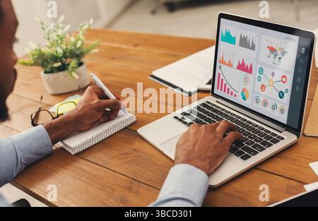 Black entrepreneur analyzing graph on laptop at workplace Stock Photo