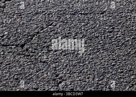 Close Up of Textured Asphalt Surface with Visible Cracks and Pebbles Stock Photo