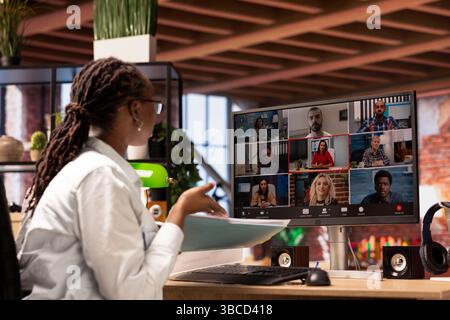 Woman at home answering videocall from board of directors checking tasks progress, showing documents. Teleworker in videoconference with management executives, presenting progress done Stock Photo