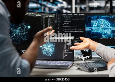 Server farm engineering team looks at data analysis graph to reduce supercomputers failure. Data center coworkers look at AI visualization dashboard to pinpoint gear performance glitches Stock Photo