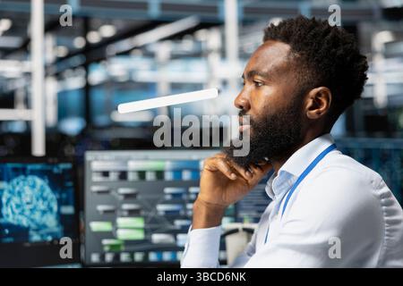 Data center workplace technician using artificial intelligence neural networks technology. Server hub specialist using AI programming language on computer, configuring specialized hardware Stock Photo