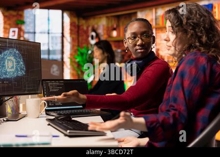 Startup software developers doing brainstorming to do rapid technological advancement in AI industry. African american woman and coworker leveraging machine learning tech to gain competitive edge Stock Photo