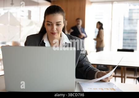 Young businesswoman using laptop working in office with papers Stock Photo