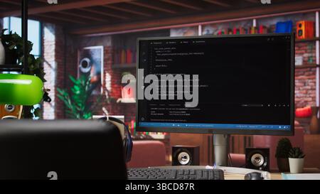 Computer desk with coding application on monitor used for creating software, implementing algorithms. Code editor on PC display used to build applications in cozy bright living room Stock Photo