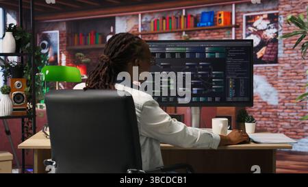 Teleworking programmer using computer for artificial intelligence computing through self learning algorithms. Remote worker working with AI deep neural networks on desktop PC, camera B Stock Photo