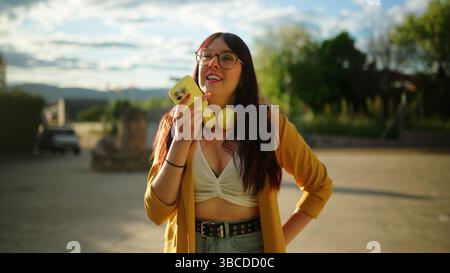 Young woman recording audio message using smartphone outdoors Stock Photo