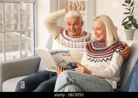 Mature couple reading magazine on sofa at home Stock Photo