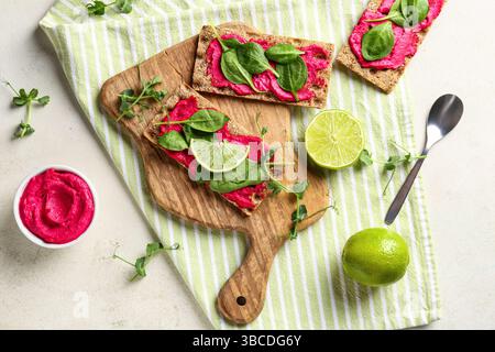 Composition with crispbreads, tasty beetroot hummus and basil on light background Stock Photo