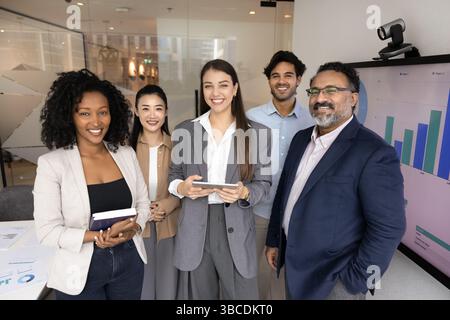 Diverse group of five businesspeople stands in modern conference room Stock Photo
