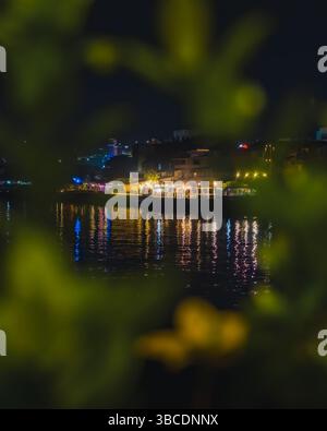 Balikpapan, Indonesia - April 21 2025. vertical shot of vibrant night scene at Balikpapan city featuring a waterfront restaurant. The lights from the Stock Photo