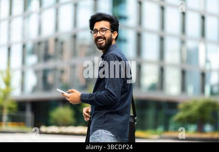 Happy middle eastern IT professional going to office, using phone Stock Photo