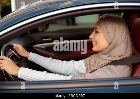 Cheerful muslim woman driving her new car Stock Photo
