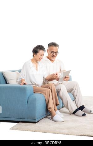 An elderly couple sitting on the sofa sharing a tablet together Stock Photo