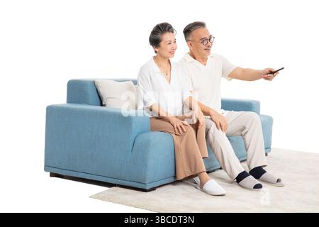 An elderly couple sitting on the sofa watching TV with a remote control Stock Photo