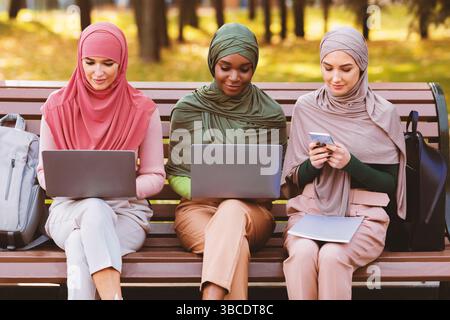 Arab Ladies Using Smartphone And Computers Learning Online In Park Stock Photo