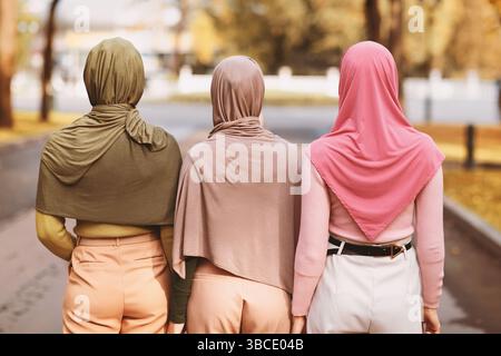 Rear-View Of Three Muslim Ladies Wearing Hijabs Walking Together Outside Stock Photo