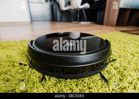 Robots vacuums cleaners on green carpet in living room for cleaning pet hair and dust. Stock Photo