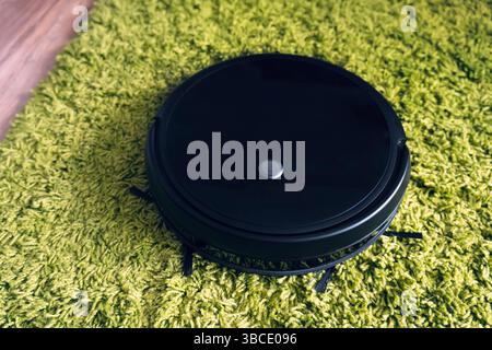 Robot vacuum cleaner on floor, Smart robotic automate wireless cleaning technology machine in living room. cleaning fleecy carpet with an automatic va Stock Photo