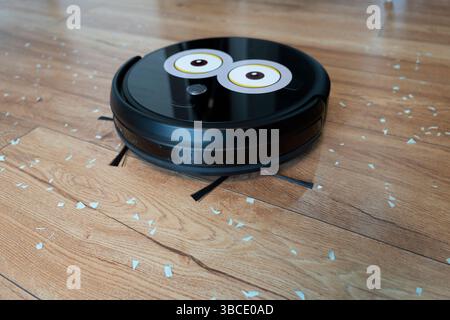 Robotic vacuum cleaner on laminate wood floor smart cleaning technology. garbage on the wooden floor. Stock Photo