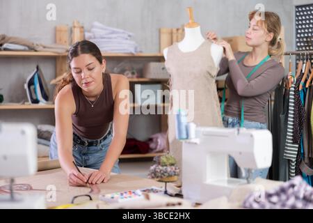 Women tailors design clothes and draw on paper in the workshop Stock Photo