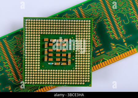 Detailed microprocessor sits atop green circuit board featuring numerous soldered connections pathways. Stock Photo