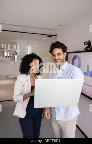 Two multiethnic young 30s professional teammates working together using laptop Stock Photo