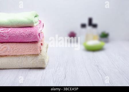 A stack of pink towels in a bathroom, accompanied by shampoo, conditioner, and soap, offering space for promotional content. Stock Photo
