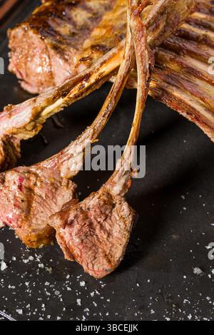 Lamb racks grilled with herbs and sauce on a stone board Stock Photo