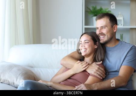 Happy couple hugging and relaxing sitting on a couch at home Stock Photo