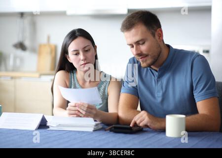 Interracial couple calculating expenses reading bill in the kitchen at home Stock Photo