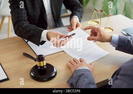 Man signing a contact with male advocate sitting on workplace in office Stock Photo