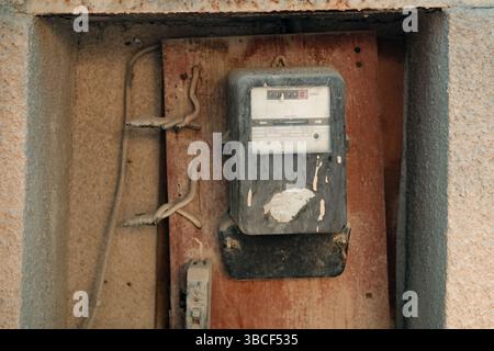 An old, dirty electric meter on a wall Stock Photo
