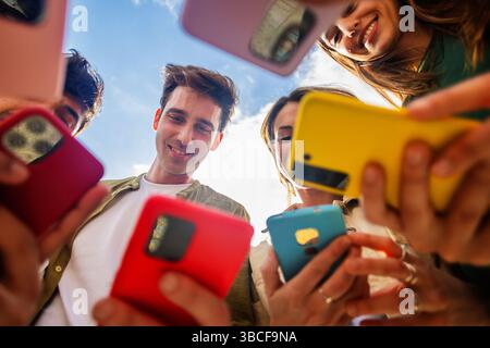 Group of young people using mobile phones together outdoors Stock Photo