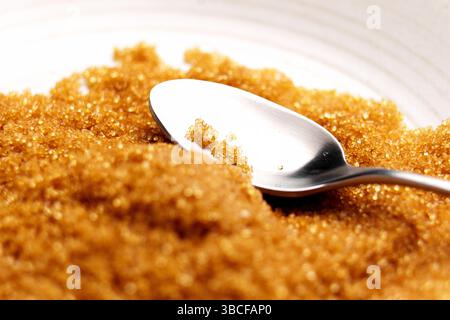 Brown cane sugar crystals with metal teaspoon. Macro shot Stock Photo