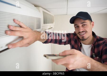 technician testing air conditioning unit with remote control Stock Photo