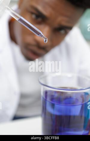 young man scientist using auto-pipette with flask in medical laboratory Stock Photo