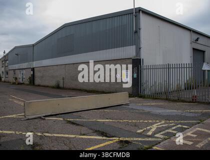 derelict concrete industrial building unit not in use with weeds growing in the cement Stock Photo