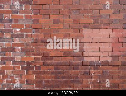 An old repaired patched exterior wall made of red bricks Stock Photo