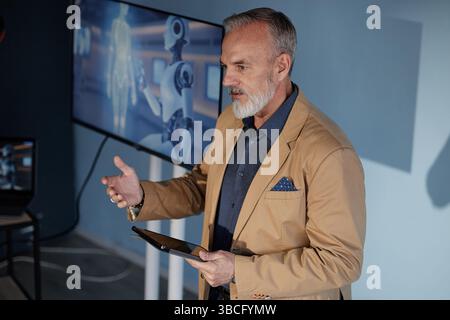 Medium shot of mature businessman dressed in stylish suit engaging audience with presentation on integrating AI innovations into modern workflow givin Stock Photo