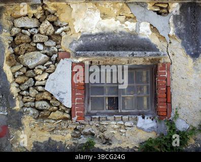 An old house with walls made from rocks with wood frame window Stock Photo