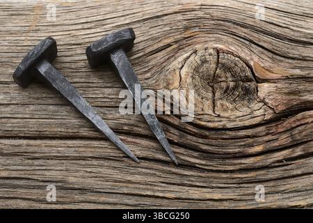 Two iron forged nails on a wooden background Stock Photo
