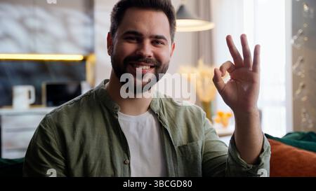 Happy satisfied Caucasian European model man male guy homeowner businessman customer client looking at camera smiling showing ok okay gesture approve Stock Photo