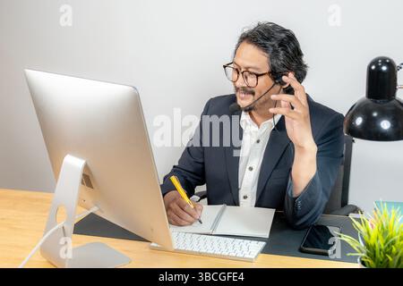 Focused and engaged — a young professional in headphones participates in a virtual business meeting Stock Photo