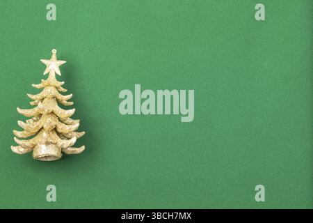 The photo shows a miniature golden Christmas tree against a green background Stock Photo
