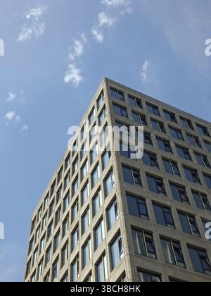 Vertical angled corner view of a white high white concrete buildings with sunlight and blue sunny sky reflected in the windows Stock Photo