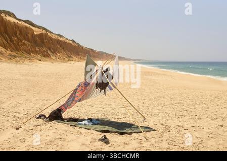 Improvised tent structure with fabric on a deserted beach under a clear sky. Portugal Stock Photo