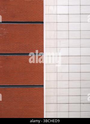 A brick red brick wall with black lines divided in half by large white modern stone tiles Stock Photo
